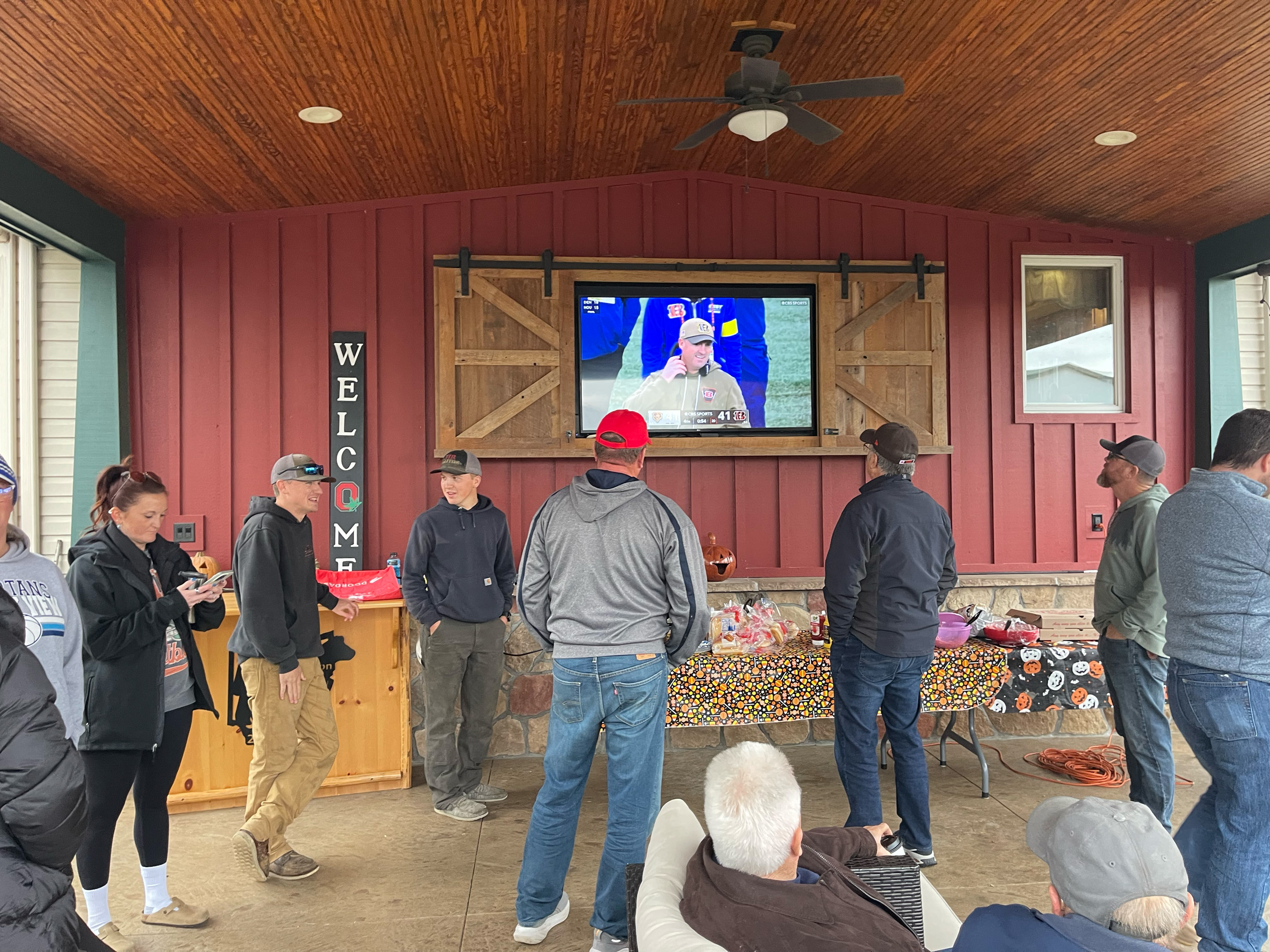 Group of people watching a football game outside on a television